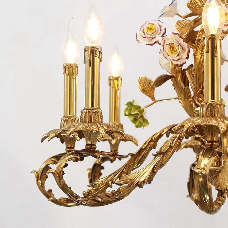 Extreme detail shot of ornate brass scrollwork, candle cups, and ceramic floral buds.
