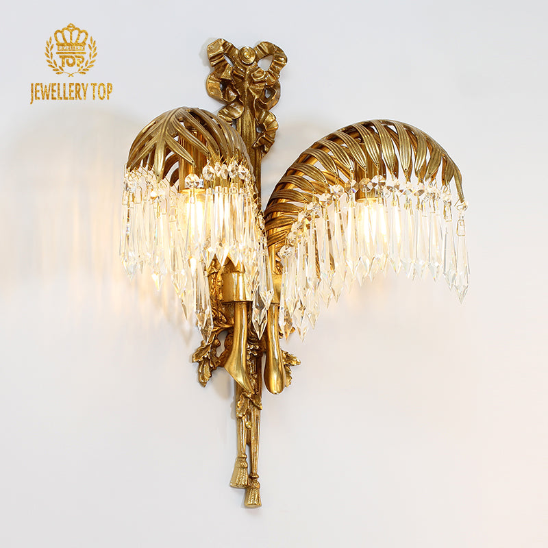 JEWELLERY TOP branded product shot of the palm leaves brass wall lamp with glowing bulb and crystal fringe.