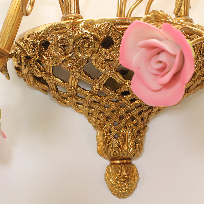 Detailed close-up of a pinecone-shaped finial and intricate metalwork on the base of the wall lamp.