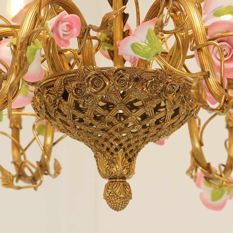 Extreme detail shot of the candle-style bulb surrounded by a decorative golden bobeche and porcelain blossoms.