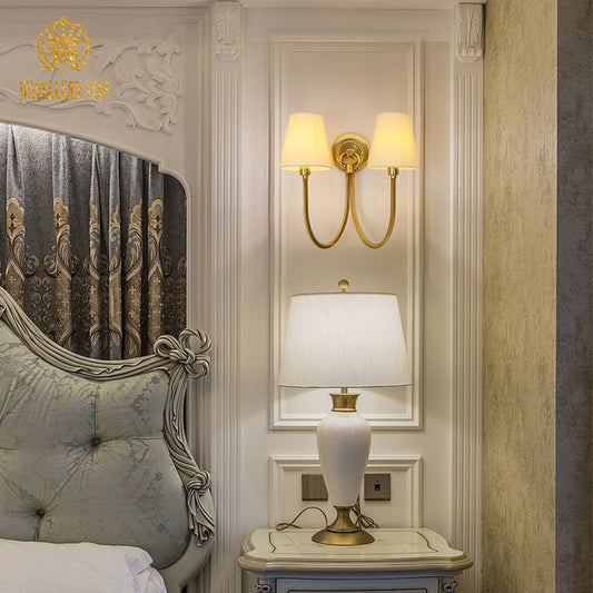 The European decorative wall sconce installed in an elegant bedroom setting with a carved headboard and side table.