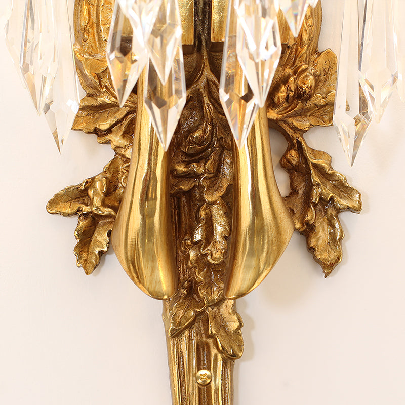 Macro shot of the clear, faceted crystal droplets suspended from the arched brass structure.
