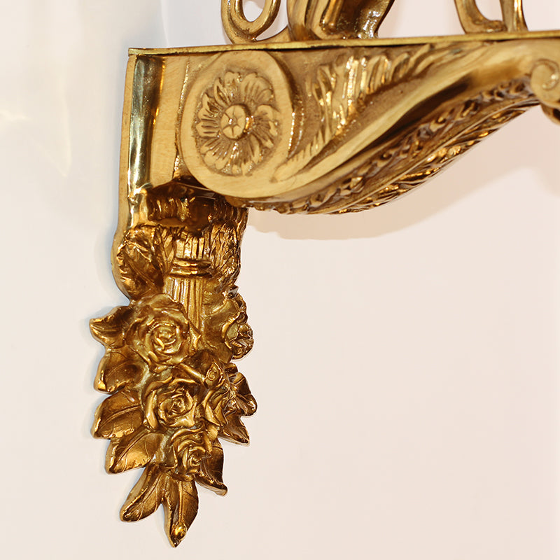 Extreme close-up of the griffon sculpture’s wing, head, and the textured base of the Victorian-style light.