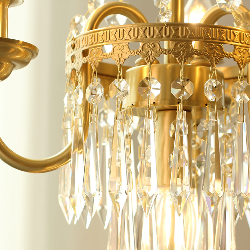 Extreme close-up of intricate brass filigree and a string of faceted crystal prisms.