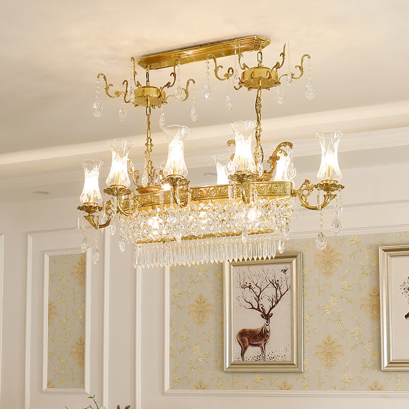 A lit classical brass chandelier with multiple lights against a patterned wall.