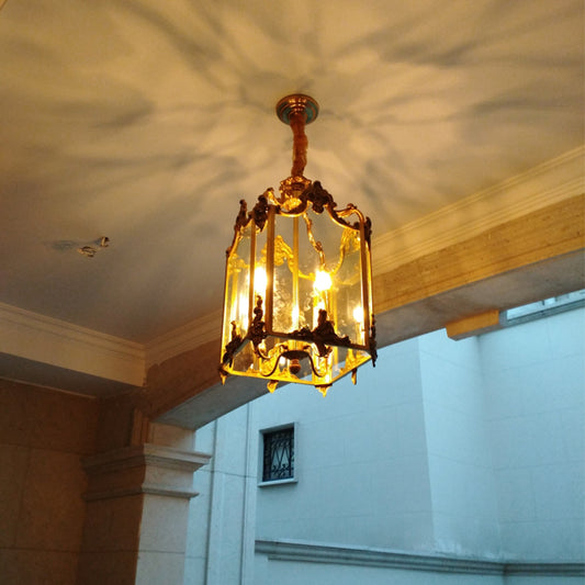 Antique brass lantern pendant light with a red cord, installed against a stone wall backdrop.