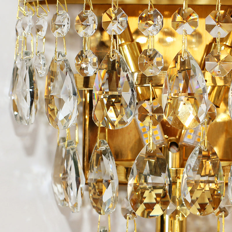 The crystal decorative wall sconce light installed on a white and gold-accented wall, emitting a soft, luxurious glow.