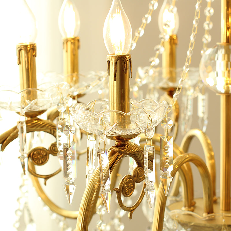Macro close-up of a single brass arm, glass candle cup, and hanging crystal teardrops.