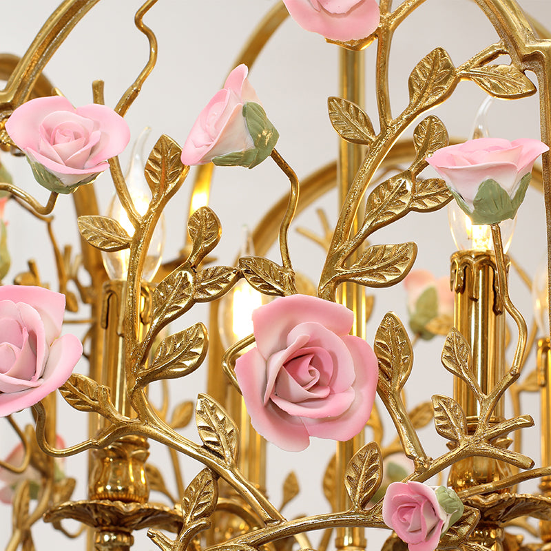 Macro close-up of the finely crafted pink rosebud and textured golden brass leaves.
