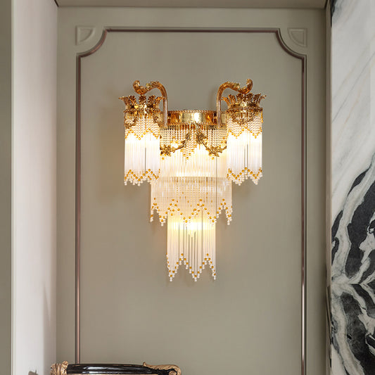 The luxury crystal wall light installed on a light gray wall with panel molding, illuminating the space with a warm, sparkling glow.