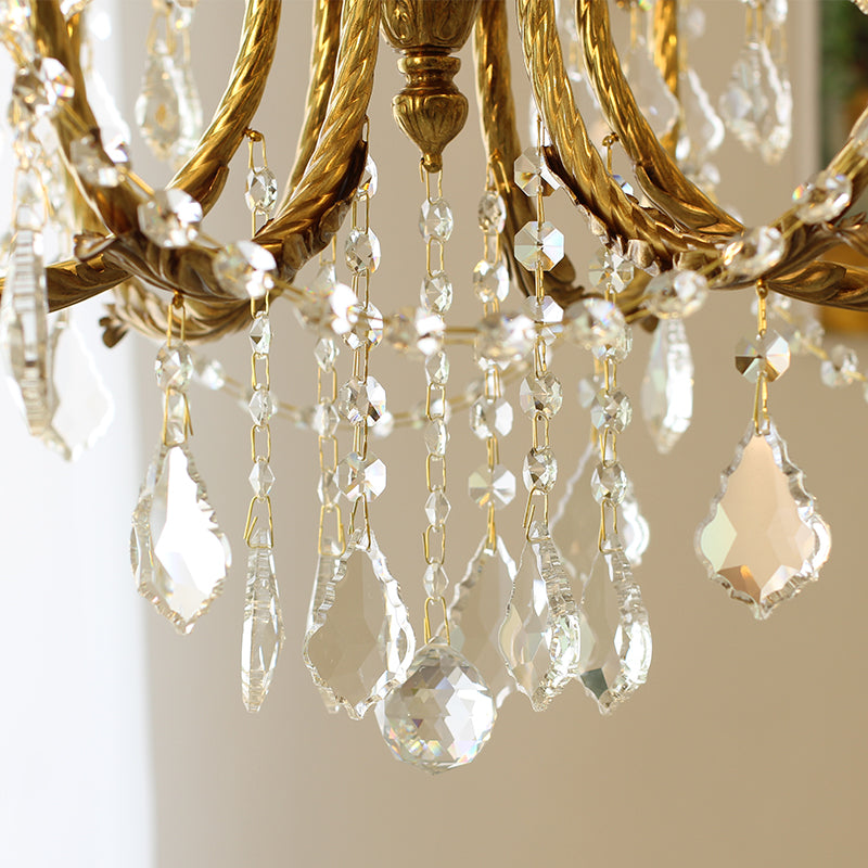 Close-up of delicate chains and geometrically cut crystal pendants on the brass chandelier.