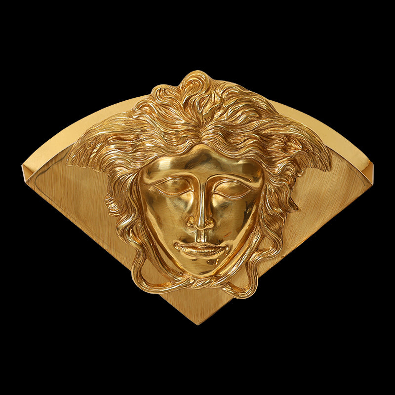 Golden brass wall sconce with a detailed closed-eye human face medallion, brand hallmarks 18K GK visible.