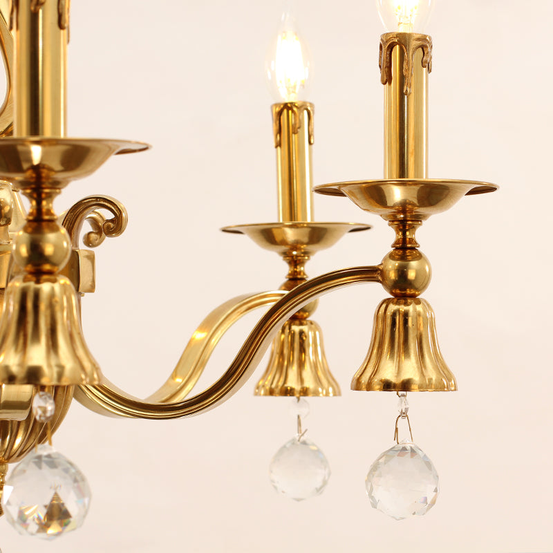 Close-up detail of a curved brass arm, candle bulb, and hanging crystal prisms.