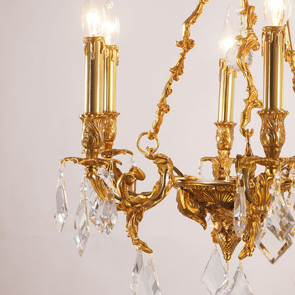 Close-up detail of a curved brass arm with leaf engraving, bulb, and crystal pendants.