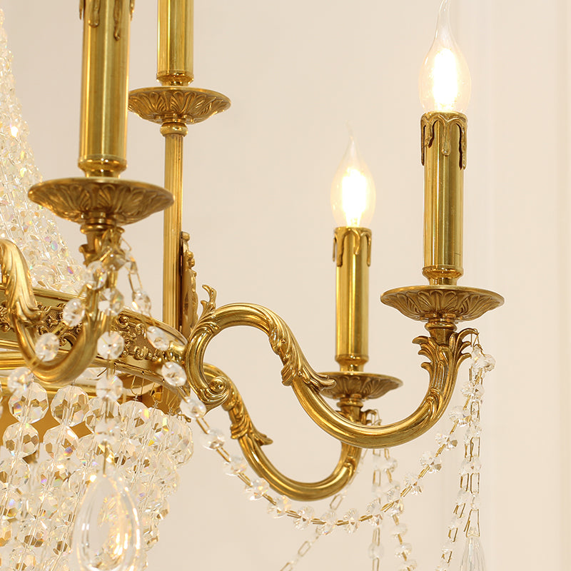 Extreme close-up of detailed brass scrollwork and a crystal teardrop on the chandelier.