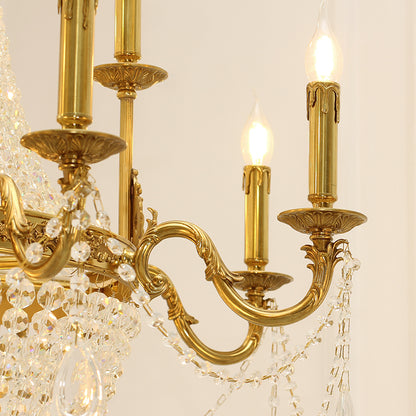 Extreme close-up of detailed brass scrollwork and a crystal teardrop on the chandelier.