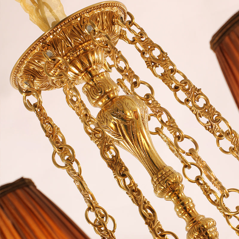 Top view detail of a brass chandelier's canopy, chains, and fabric accent from JEWELLERY TOP.