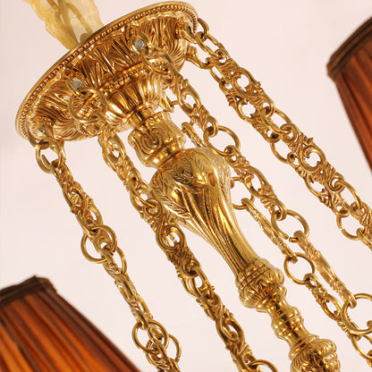 Top view detail of a brass chandelier's canopy, chains, and fabric accent from JEWELLERY TOP.