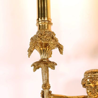 Extreme close-up of the lamp’s ornate arm, highlighting the intricate leaf carving, grape clusters, and golden brass patina.