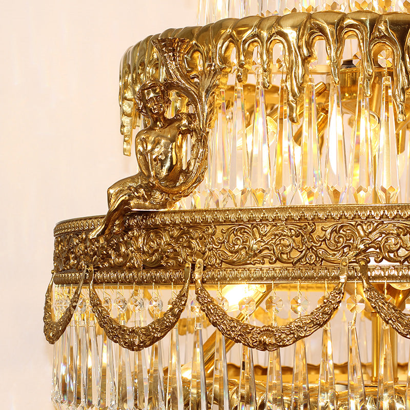 Close-up detail of a cherub statue on ornate brass scrollwork with crystal drops.