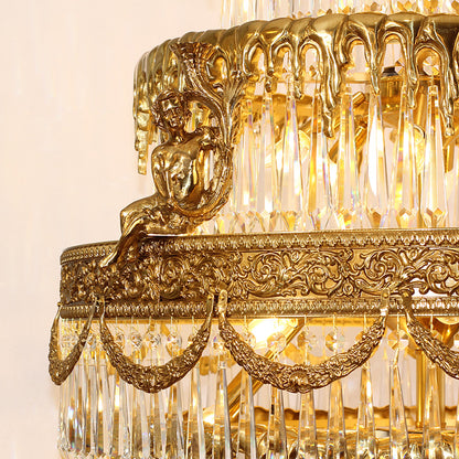 Close-up detail of a cherub statue on ornate brass scrollwork with crystal drops.