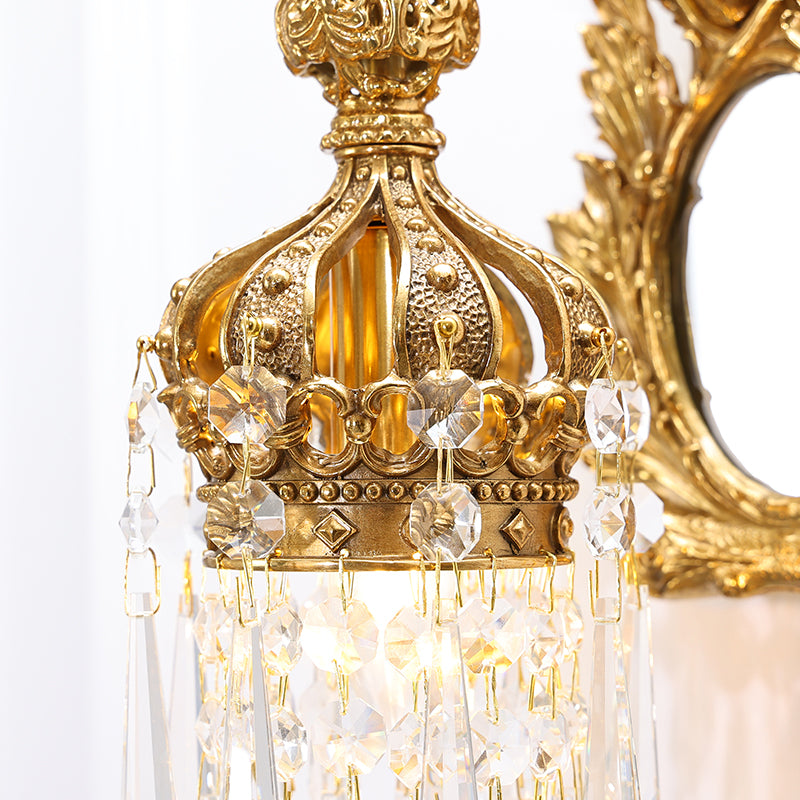 Detailed shot of the crystal droplet fringe and the leaf-engraved mirror frame on the sconce.