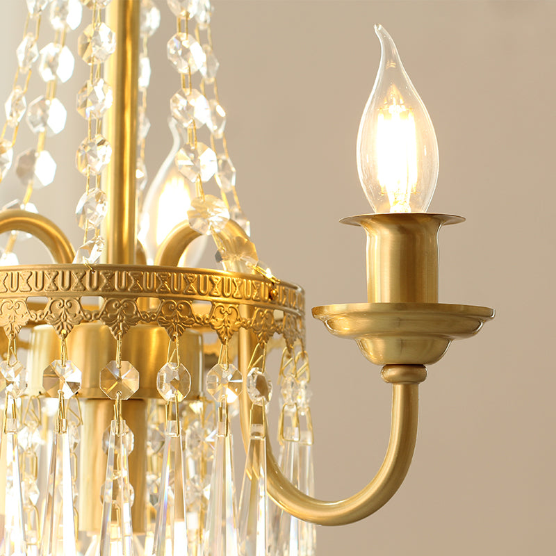 Detailed macro shot of a brass arm, candle bulb, and layered crystal pendants.