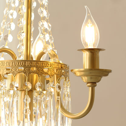 Detailed macro shot of a brass arm, candle bulb, and layered crystal pendants.