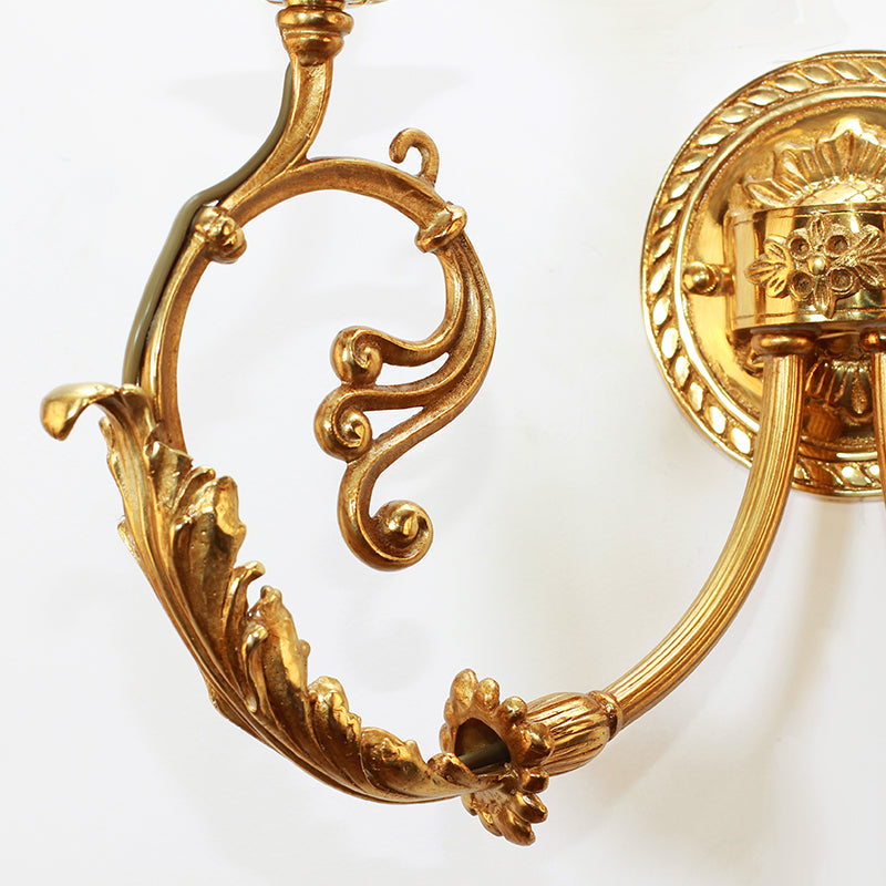 Detailed shot of a single scrolled brass arm, showcasing the deep-relief leaf carvings and golden finish of the sconce.