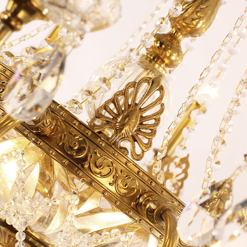 Macro detail of ornate brass scrollwork and hanging crystal strings on a chandelier arm.
