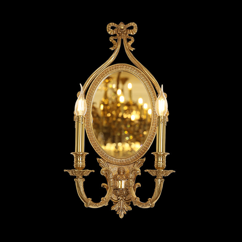 Front view of the JEWELLERY TOP Butterfly Bow brass wall sconce with oval mirror and candle lights, reflecting a warm glow.