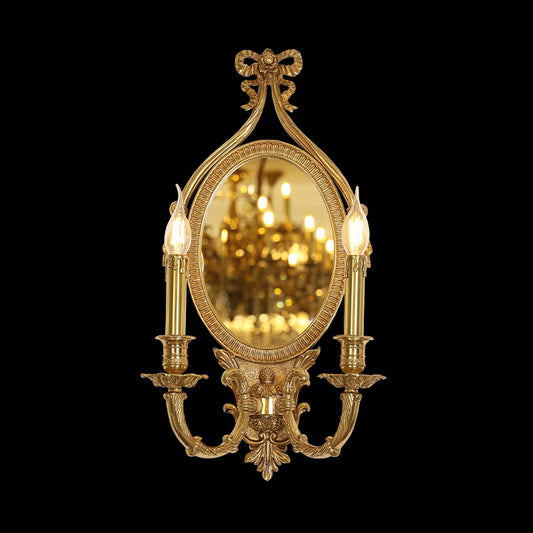 Front view of the JEWELLERY TOP Butterfly Bow brass wall sconce with oval mirror and candle lights, reflecting a warm glow.