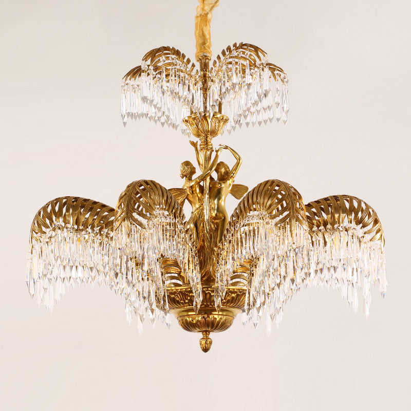 Detailed shot of the luxury brass chandelier featuring two feminine figures amidst palm leaf motifs.