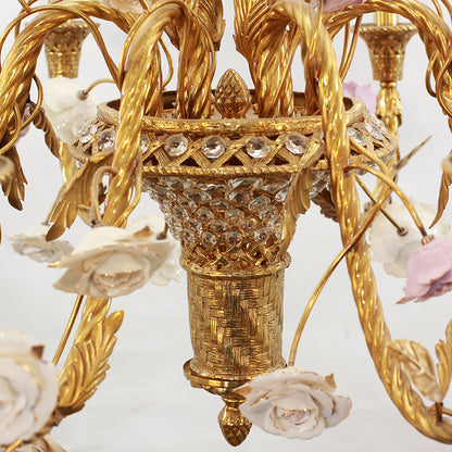 Extreme close-up macro of the chandelier's ornate brass centerpiece with textured vase and ceramic roses.