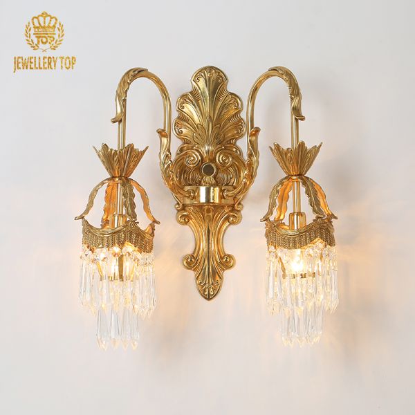 Close-up of the brass sconce’s central engraved medallion and symmetrical crystal cascades.