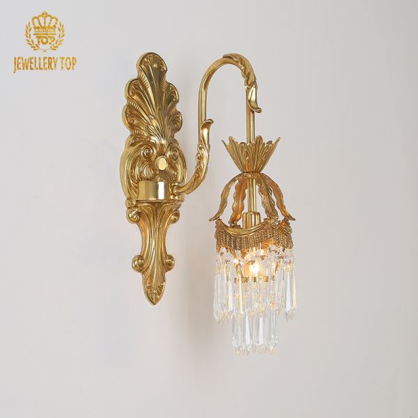 Macro detail of the intricate scrollwork and leaf carvings on the golden bronze wall light.