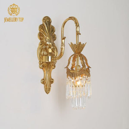 Macro detail of the intricate scrollwork and leaf carvings on the golden bronze wall light.