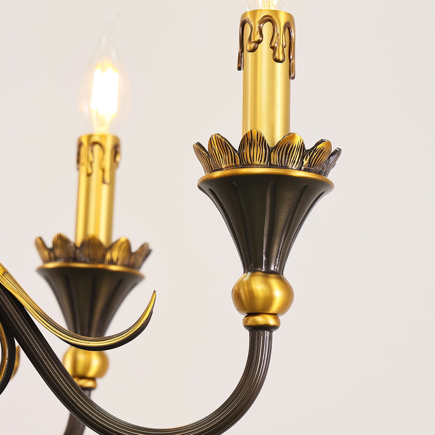 Extreme close-up detail of a curved brass arm and textured candle bulb on a vintage chandelier.