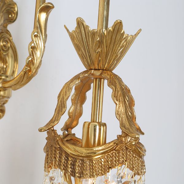 Extreme close-up of the sparkling crystal fringe and the polished brass arm of the luxury lamp.
