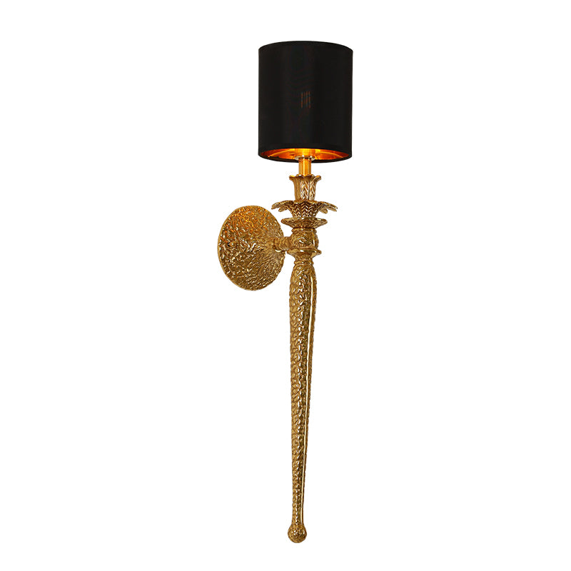 Detailed macro photography of the sconce’s hammered-texture brass backplate and ornate scrollwork arm.