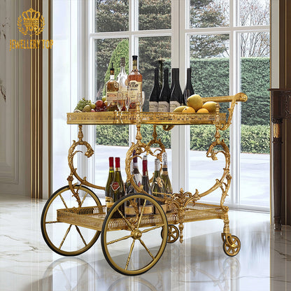 Lifestyle image of The Dionysus brass bar cart loaded with fine wines and glassware in a luxury room by Jewellery Top.
