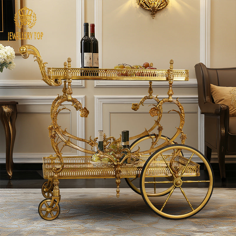 Side profile view of the French Rococo brass wine trolley next to a tufted armchair by Jewellery Top.