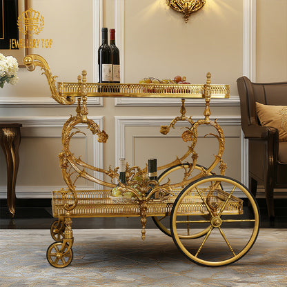 Side profile view of the French Rococo brass wine trolley next to a tufted armchair by Jewellery Top.