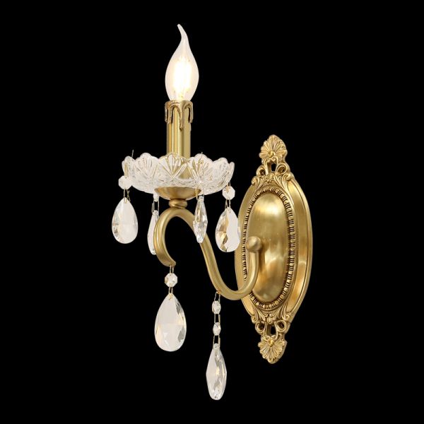 Close-up detail of the wall lamp’s glowing candle bulb and suspended crystal teardrop decorations.
