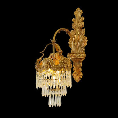 Isolated front view of the Rococo Maestro brass wall sconce with a classical mascaron and crystal cascades on black.