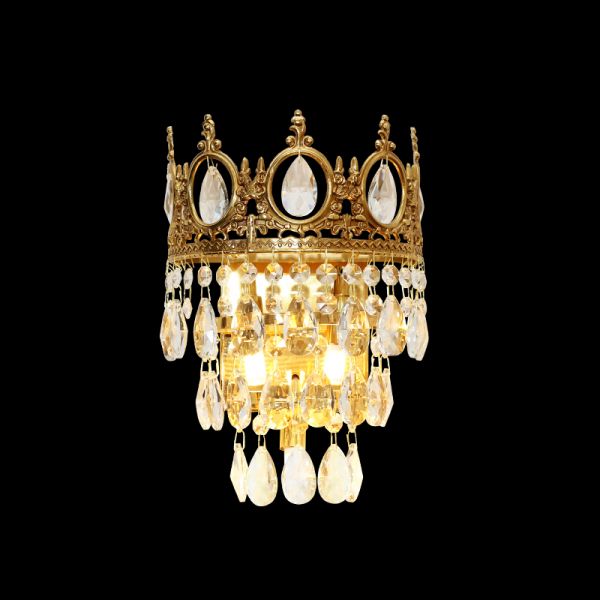 The full Couronne de Lumière brass wall sconce with a golden crown top and cascading crystal droplets on a dark background.
