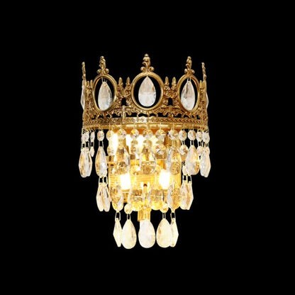 The full Couronne de Lumière brass wall sconce with a golden crown top and cascading crystal droplets on a dark background.