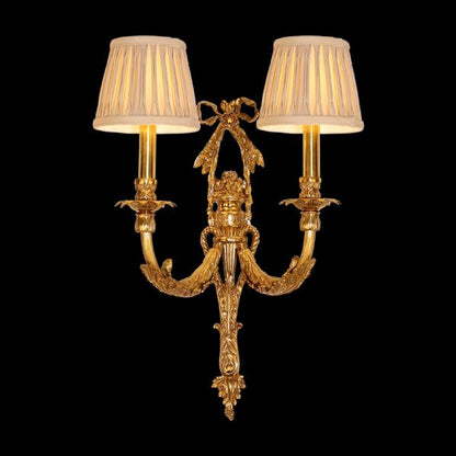 Front view of the Rococo Bow & Bough brass wall sconce with a central bow and two fabric shades on a dark background.
