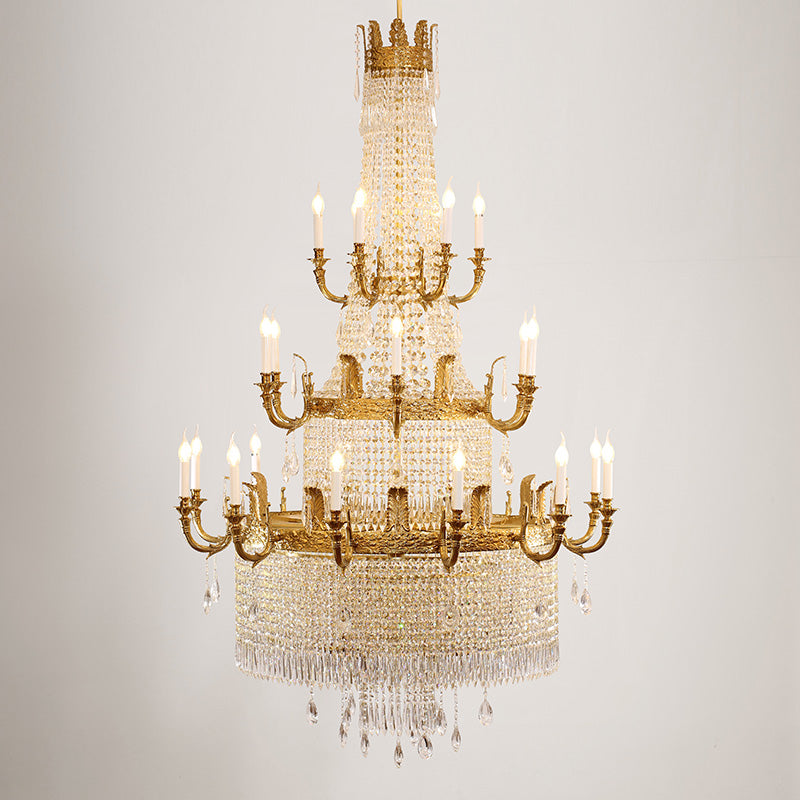French Baroque brass chandelier against a white wall, showcasing its crystal and gold details.