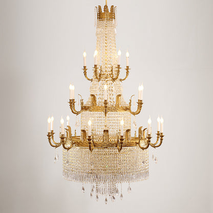 French Baroque brass chandelier against a white wall, showcasing its crystal and gold details.